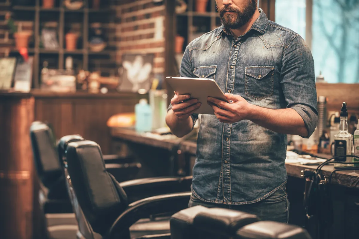 Barbero revisando su agenda en una tablet dentro de la barbería